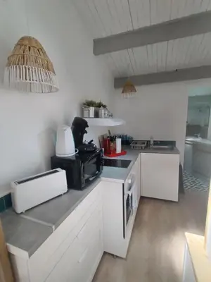 a kitchen with white cabinets and a black microwave at La Ch'tite Maison in Céreste
