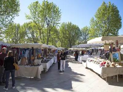 a group of people walking around a market with tables at La Pineda de Provence in Aix-en-Provence