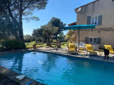 a swimming pool with yellow chairs and an umbrella at Petite Maison provencale in Lagnes