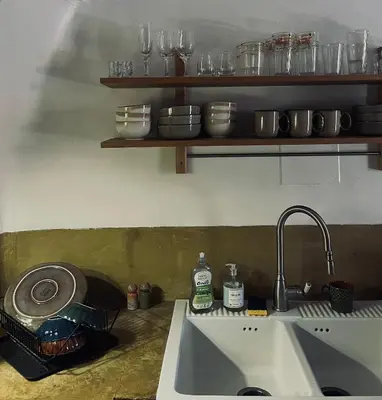 a kitchen counter with a sink and a shelf with glasses at La Biscornue in Lauris