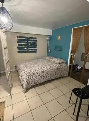 a bedroom with a bed and a blue wall at Studio cosy avec coin nuit in Pélissanne