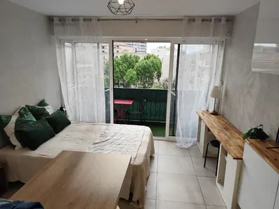 a bedroom with a bed and a table and a balcony at Studio plein centre in Aix-en-Provence