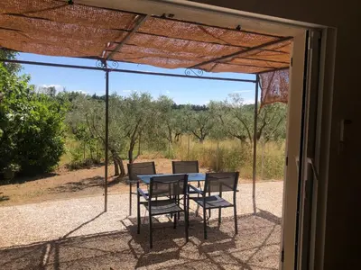 a table and chairs on a screened in porch at L'olivier in Aureille