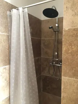 a shower with a shower curtain in a bathroom at L'olivier in Aureille