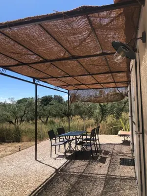 a patio with a table and chairs under a roof at L'olivier in Aureille