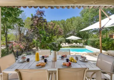 a table with food on it next to a swimming pool at Villa La Belle Vie in Gordes