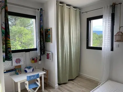 a bedroom with a window and a table and a desk at La villa dans les arbres - Triangle d'or du Luberon in Ménerbes
