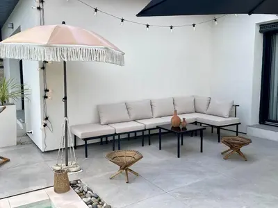 a patio with white couches and a table and an umbrella at Villa rosalie L'Isle-sur-la-Sorgue in LʼIsle-sur-la-Sorgue