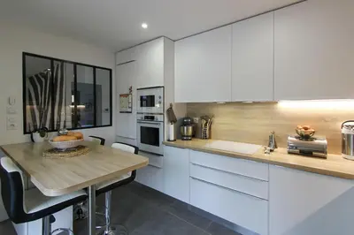 a kitchen with white cabinets and a wooden counter top at Villa rosalie L'Isle-sur-la-Sorgue in LʼIsle-sur-la-Sorgue