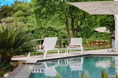 two chairs and an umbrella next to a swimming pool at Villa contemporaine de luxe in Aix-en-Provence