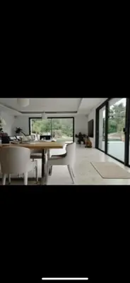 a dining room with a table and chairs and windows at Villa contemporaine de luxe in Aix-en-Provence