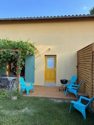 a deck with blue chairs and a yellow door at Au doux paillis soleil couchant in Le Thor
