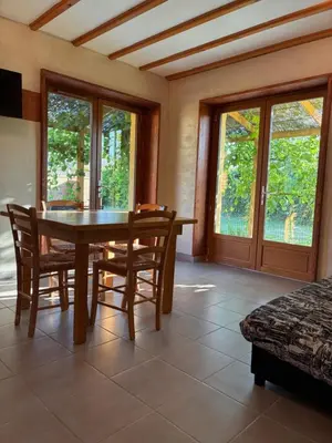 a dining room with a table and chairs and windows at Au doux paillis soleil couchant in Le Thor