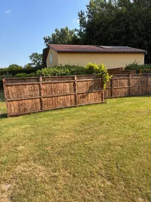 a wooden fence in front of a house at Au doux paillis soleil couchant in Le Thor