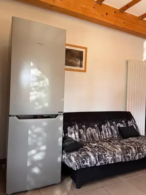 a refrigerator next to a couch in a room at Au doux paillis soleil couchant in Le Thor