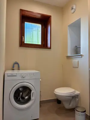 a bathroom with a washing machine and a toilet at Au doux paillis soleil couchant in Le Thor