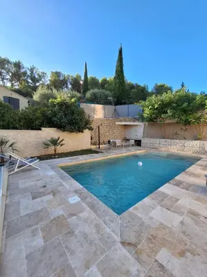a swimming pool in a yard with a stone wall at Fontaine de bonheur in Fontaine-de-Vaucluse
