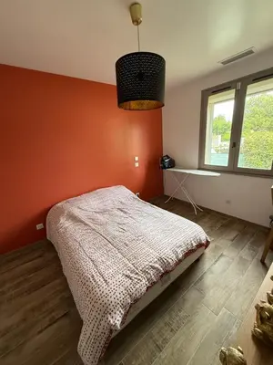 a bedroom with an orange wall with a bed in it at La Tobynette in LʼIsle-sur-la-Sorgue