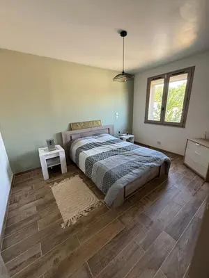 a bedroom with a large bed and a wooden floor at La Tobynette in LʼIsle-sur-la-Sorgue