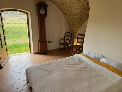 a bedroom with a bed and a grandfather clock at Bastide Neuve au Cœur du Luberon - Piscine Privée in Lauris