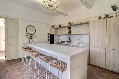 a kitchen with a large white counter and stools at Château vert in Cavaillon