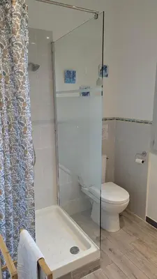 a bathroom with a toilet and a glass shower at Gite Le Petit Luberon LISIANTHUS in Cabrières-dʼAvignon