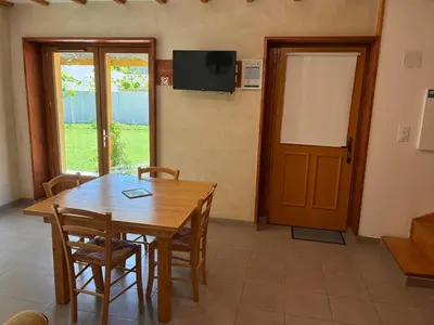 a dining room with a wooden table and a door at Au doux paillis Sorgue in Le Thor