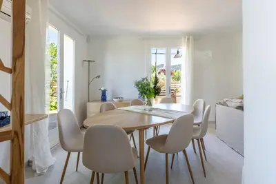 a white dining room with a wooden table and chairs at La Note Bleue Luberon in Maubec