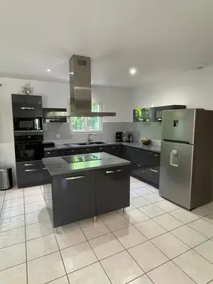 a large kitchen with black and stainless steel appliances at Maison de vacances in Le Thor