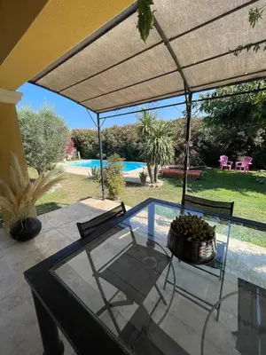 a patio with a glass table and chairs and a pool at Maison de vacances in Le Thor