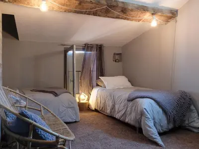 a bedroom with two beds and a chair in it at La Grande Bergerie in Saint-Saturnin-les-Apt
