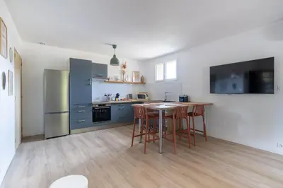 a kitchen with a table and a refrigerator at Maison proche Avignon Clim Terrasse wifi 4pers in Jonquerettes