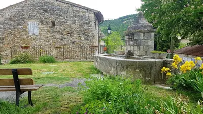 a stone building with a fountain in a yard with a bench at Maison conviviale avec jardin à Revest-des-Brousses in Vachères