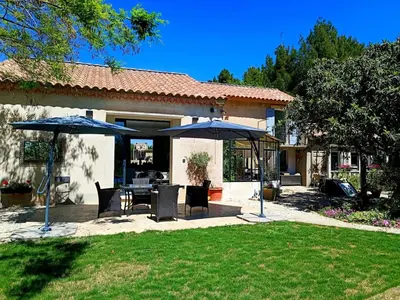 a patio with tables and umbrellas in a yard at Ville au calme en Provence, piscine privée, spa jeux, proche Ventoux in Carpentras