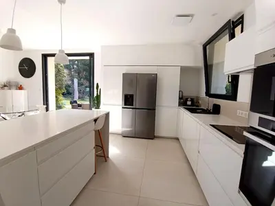 a kitchen with white cabinets and a stainless steel refrigerator at Ville au calme en Provence, piscine privée, spa jeux, proche Ventoux in Carpentras