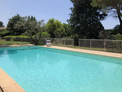 a swimming pool with a chair in a yard at Gîte 6 pers en Provence avec grande piscine partagée avec 2nd gîte - 6 pers house in Provence with a large swimming pool to be shared with a 2nd house in Cornillon-Confoux