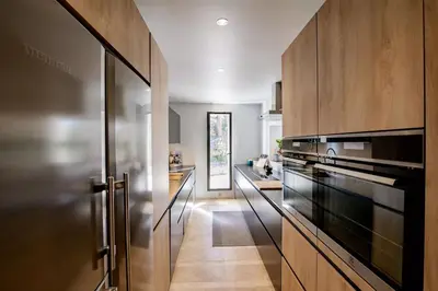 a kitchen with wooden cabinets and black appliances at Exceptional Bastide in Lourmarin, Luberon in Lourmarin