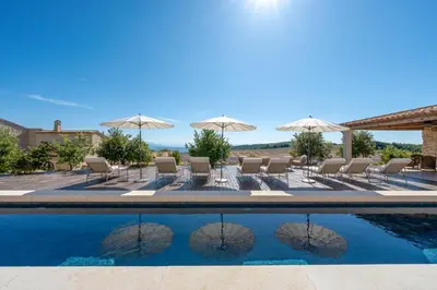 a villa with a pool and chairs and umbrellas at Domaine Château du Bois Provence in Lagarde-dʼApt