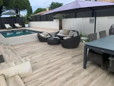 a patio with a table and chairs and a swimming pool at Maison agréable pour vacances réussies in Vernègues