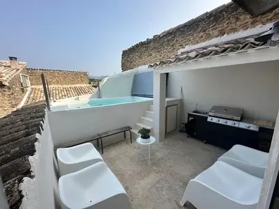 a balcony with a swimming pool and white chairs at Les Romarins - 5 chambres in Lauris