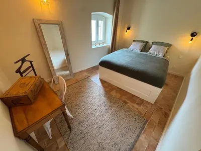a bedroom with a bed and a table and a mirror at Les Romarins - 5 chambres in Lauris