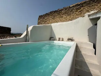a swimming pool next to a stone wall at Les Romarins - 5 chambres in Lauris