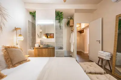 a bathroom with a large white bed and a sink at La Cour Secrète - Suite Bali Balnéo privé Carpentras in Carpentras