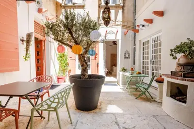 a courtyard with a table and a tree in a pot at La Cour Secrète - Suite Riad Balnéo privé Carpentras in Carpentras
