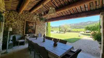 a wooden table and chairs in a room with a large window at Mas aux gourmandises in Oppède