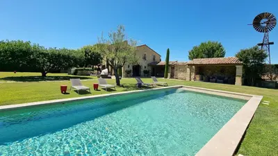 a swimming pool with chairs and a windmill at Mas aux gourmandises in Oppède