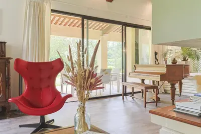 a living room with a red chair and a piano at Villa des Pres in Eyragues