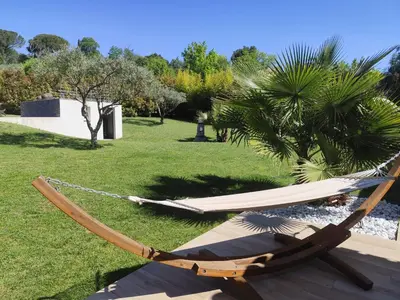 a hammock sitting on the grass in a yard at Chamarte villa piscine chauffées jardin clôturé Aix en Provence in Aix-en-Provence