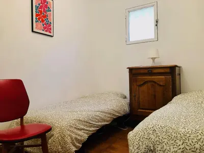 a bedroom with two beds and a red chair at Villa Le Pin in Rognes