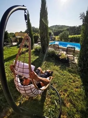 a man laying in a hammock by a pool at appartement avec piscine in Gargas